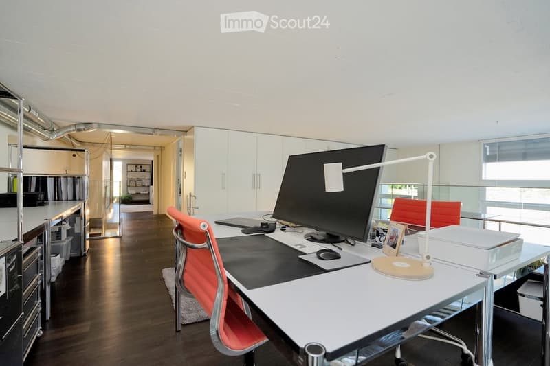 modern office space with black desk, orange chairs, computer setup, lamps, cabinets, glass window