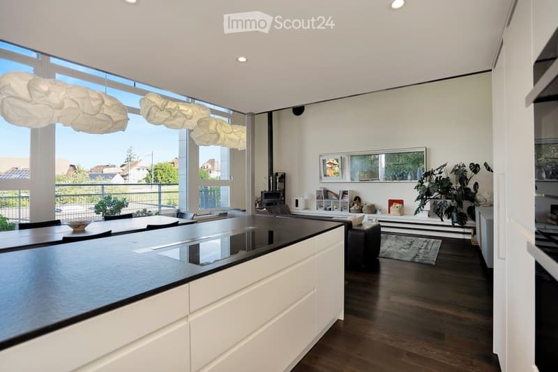 modern kitchen with large black countertops, white cabinets, chandeliers, balcony with outside view, large windows