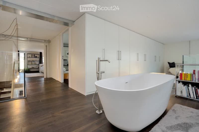white bathtub, large white cabinet, wooden floor, glass wall, chrome faucet