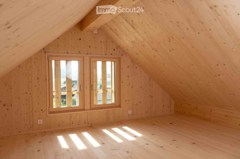 unfinished attic room, wooden walls, two windows, beams on the ceiling