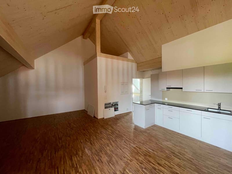 empty kitchen with wooden floors and white kitchen cabinets, black countertops, and silver sink and faucet