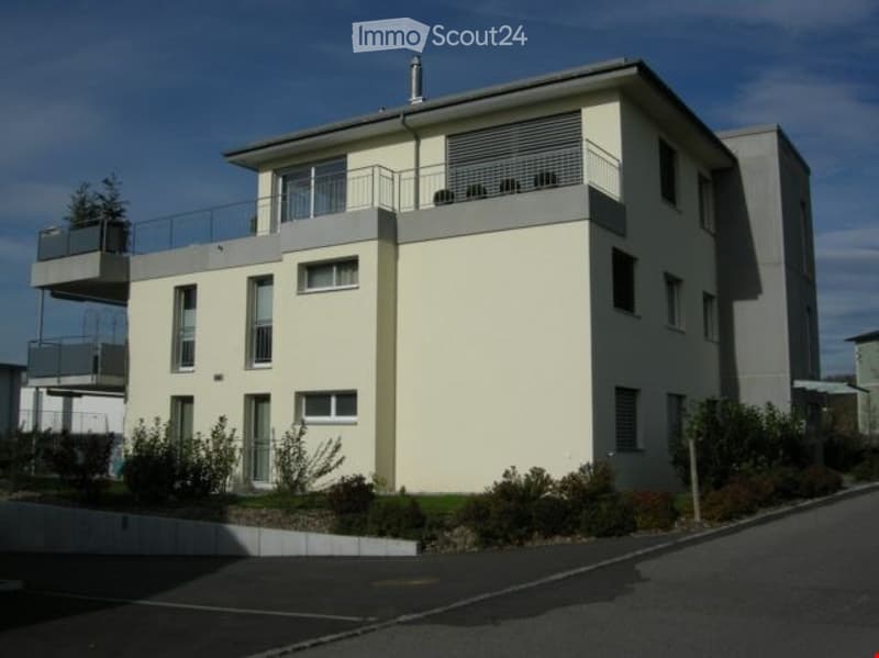 white building, three floors, balcony, windows, outdoor plants, parking in front