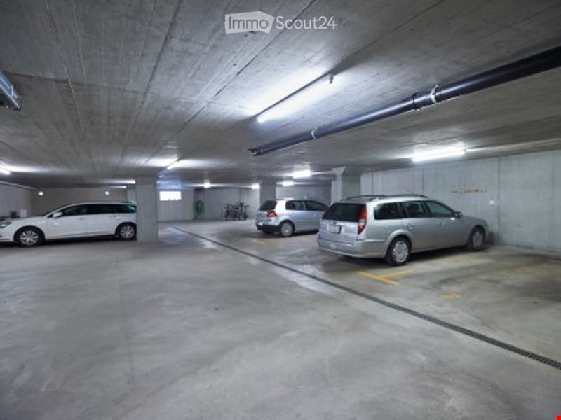 large parking spaces, concrete walls, ceiling lamps, parking spots for bicycles
