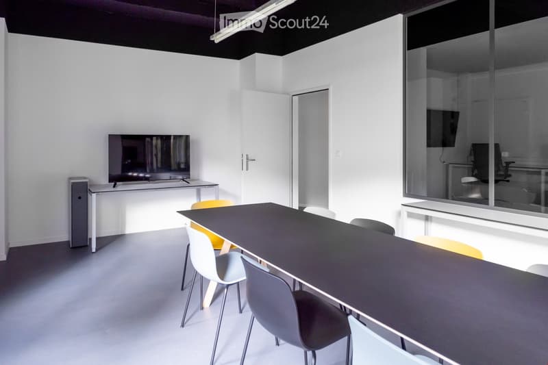 white walls, gray floor, large table with chairs, television on stand, doorways, glass walls