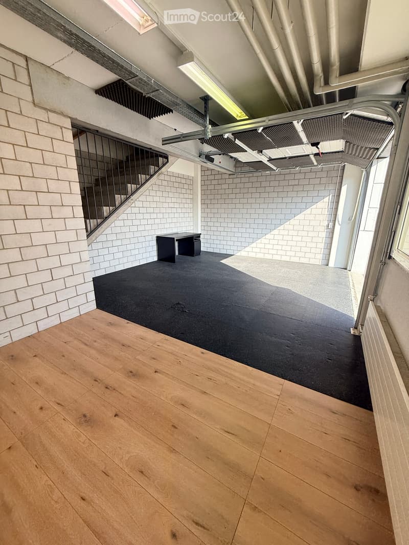 concrete floor, black carpet, wooden floor, stairs, black desk, pipes on ceiling