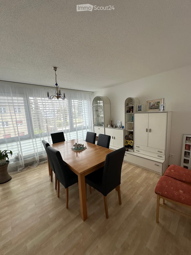 dining room with wooden table and chairs, wooden flooring, chandelier, large window, cabinets with shelves