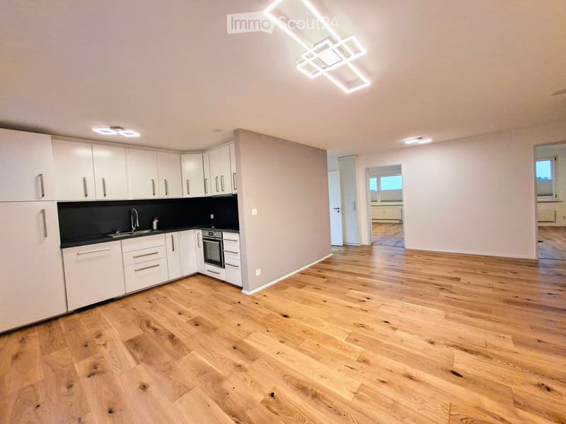 kitchen with wooden floor, white cabinets, black countertops, built-in oven, dishwasher, and washing machine