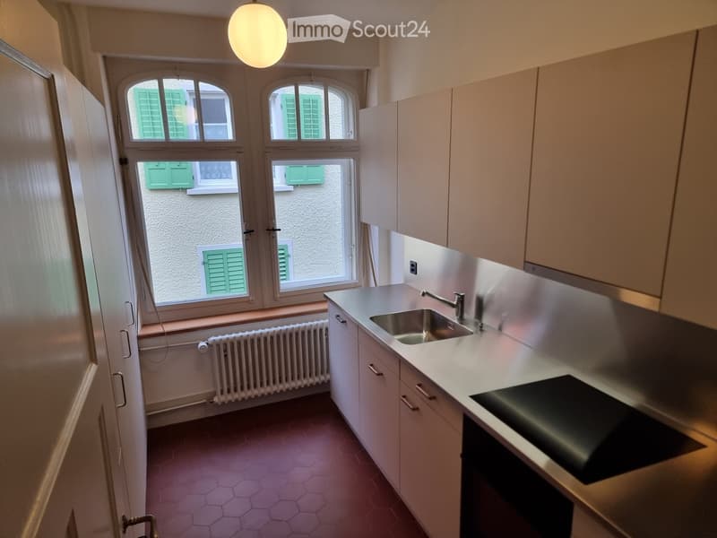 small kitchen with white cabinets, silver countertop, modern sink and faucet, stove, kitchen window, underfloor heating