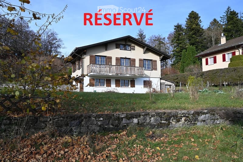 2 story house, white exterior, brown shutters, balcony, stone wall, grassy area, trees