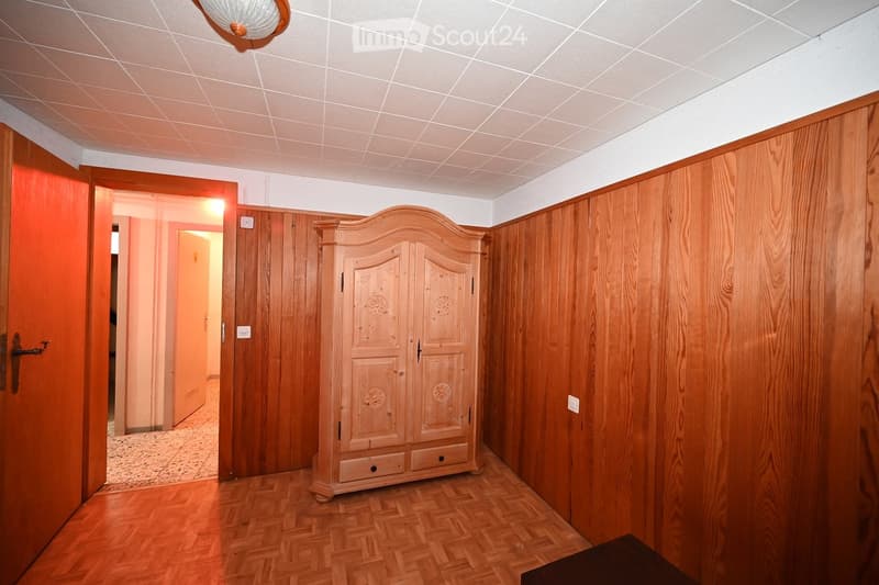 Empty room with wooden walls, wooden parquet floor, large wardrobe