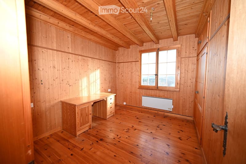 empty room with wooden walls, wooden floor, wooden desk, radiator, window