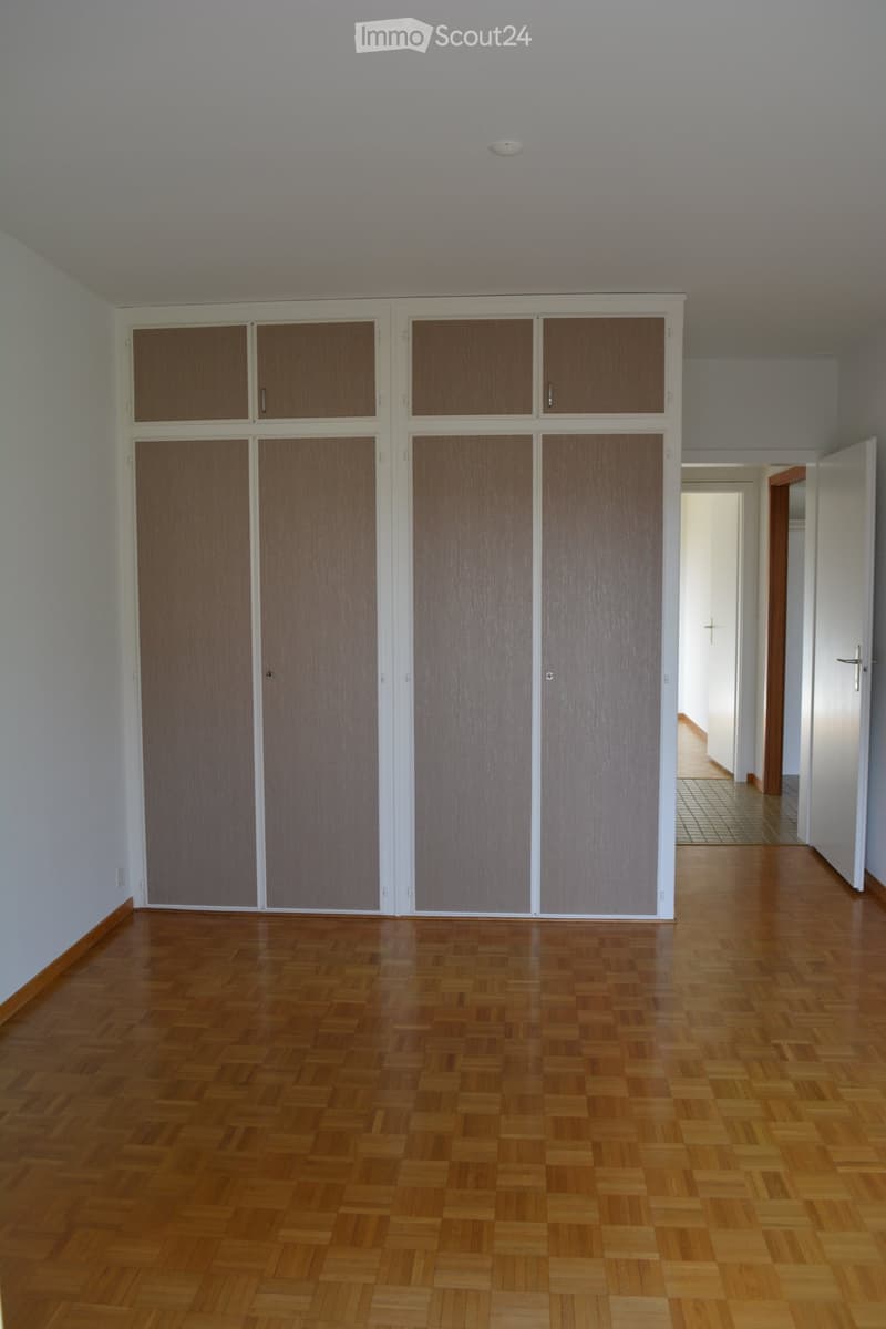 Empty room with large built-in wardrobes, parquet floor, white walls