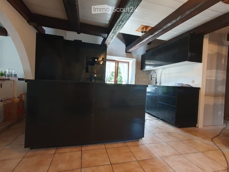 large black island, wooden ceiling beams, white tile flooring, open cupboards, modern kitchen appliances