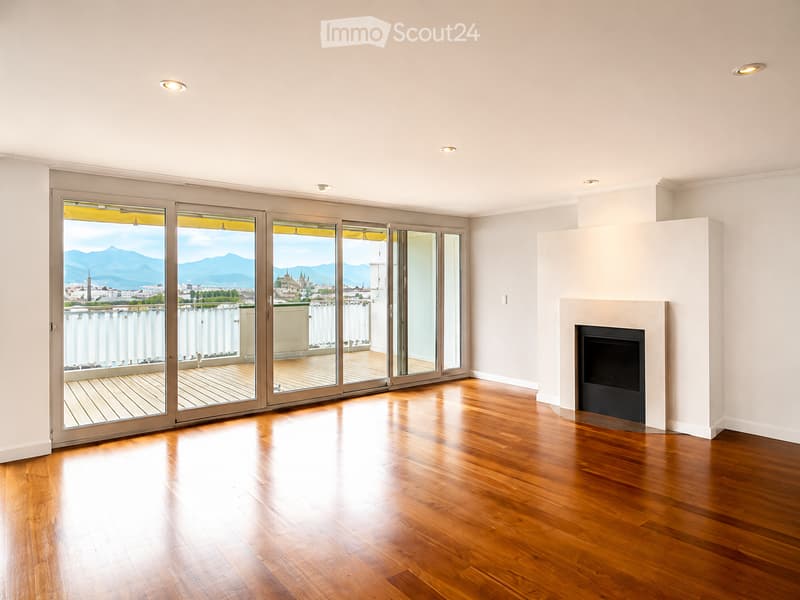 Unfurnished Room. Empty room with wooden flooring, large sliding glass doors leading to a balcony, fireplace, and scenic mountain view.