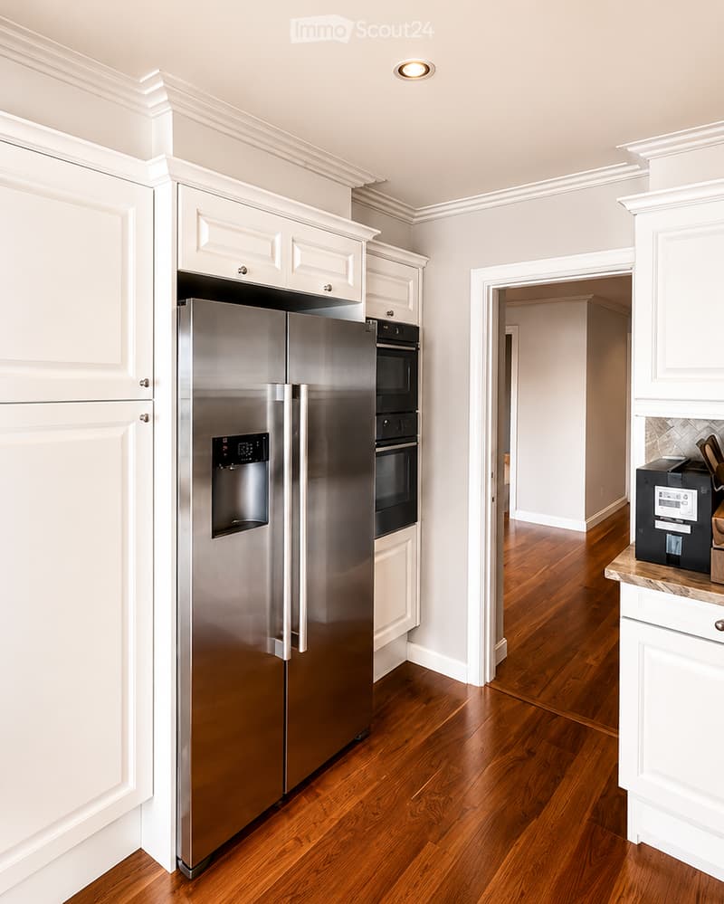 Kitchen. Modern kitchen with white cabinets, stainless steel refrigerator, built-in oven, and wooden flooring.