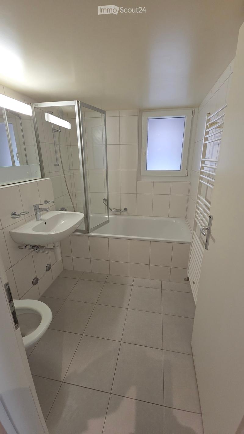 Clean bathroom with tiled walls and floor, bathtub, shower, sink, and toilet.
