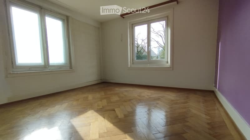 large room with parquet floor, two windows, empty