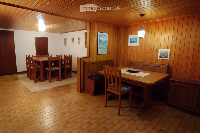 Furnished Room. Wooden dining table with chairs, a bench, and a lamp. A rug is under the table. A cabinet is on the right side.
