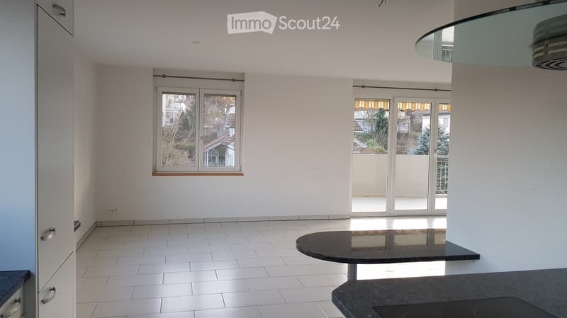 empty room, white tiles, white cabinets, black table, large glass doors leading to balcony
