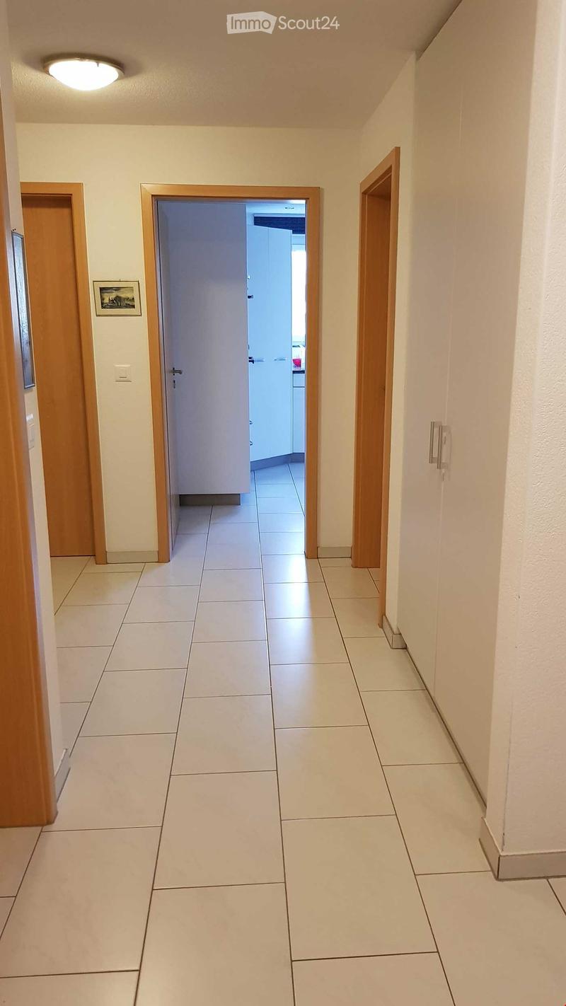 wide hallway, white tiles, wooden doors, closets, light on ceiling, open door