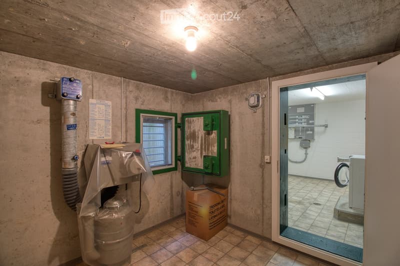 Concrete walls and tiled floor, small room, washing machine in adjacent room