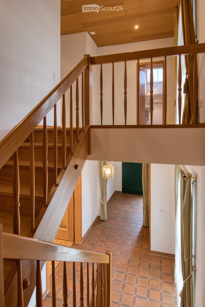 double staircase, wooden rails, tiled floor, balcony with railing, wooden ceiling