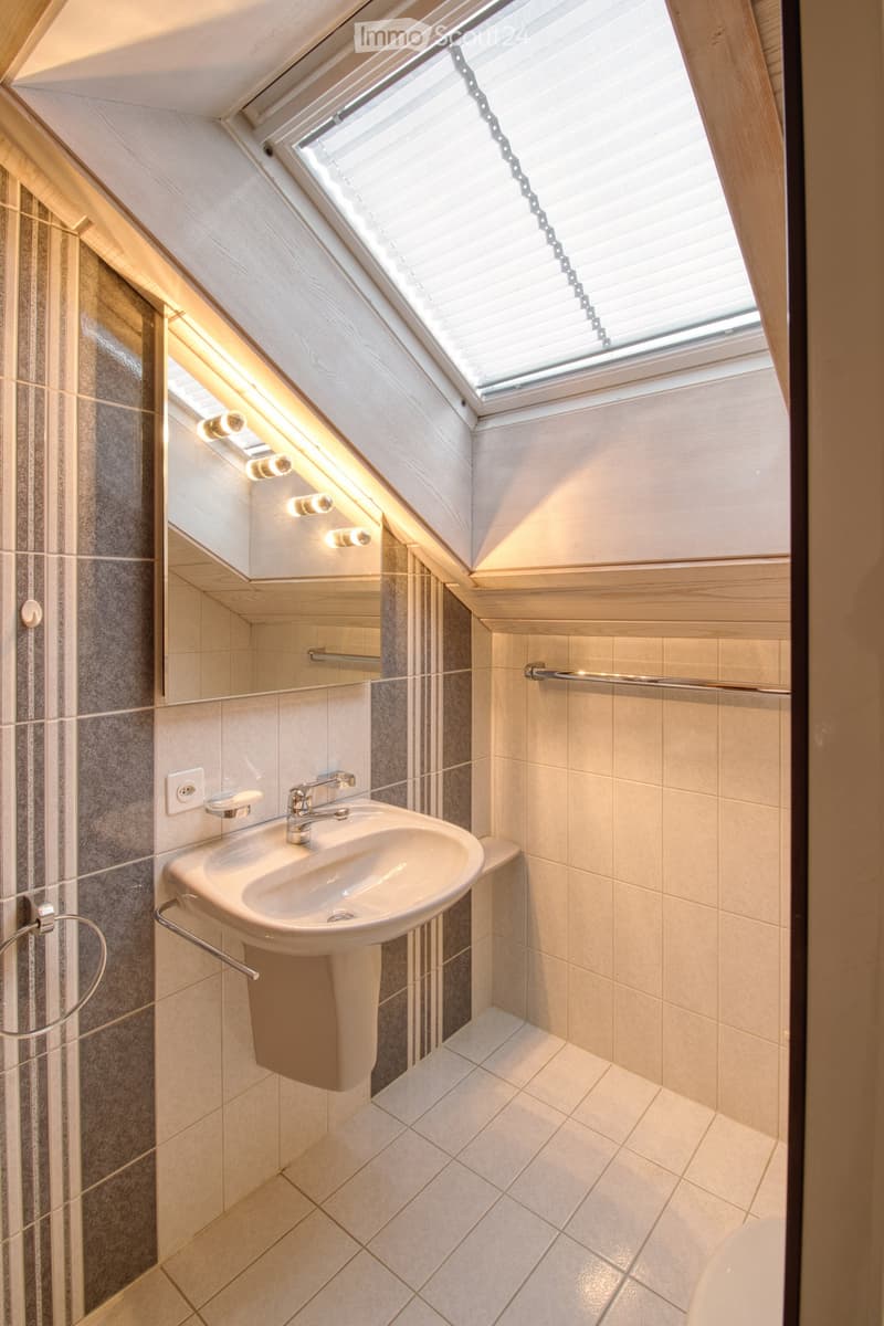 Bathroom with white sink, mirror, white shower enclosure, white tile flooring, white showerhead, white toilet bowl, and ceiling skylight