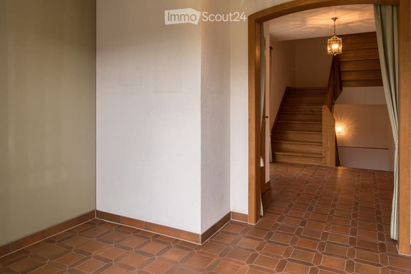interior with tiled flooring, wooden staircase, open doorway with lamp