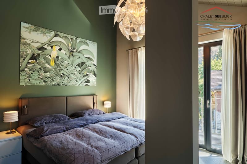 large double bed, bedside lamps, bedside nightstand, decorative painting, large window with balcony