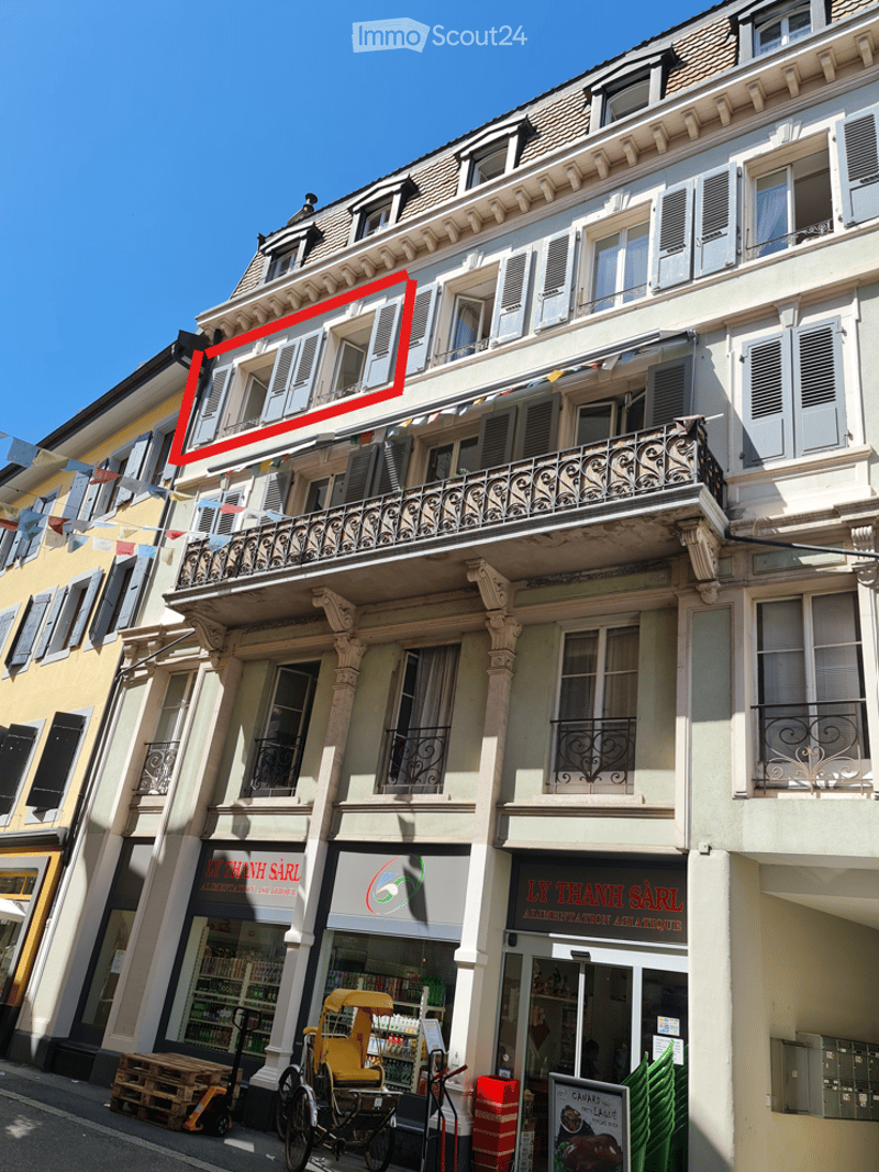 4 story building, white exterior, multiple balconies, ground floor shops, highlighted apartment on 3rd floor