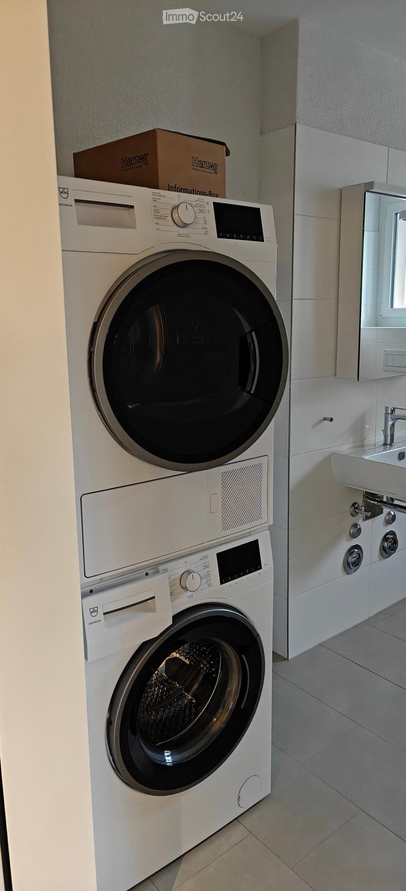 Stacked washer and dryer in laundry room, sink with faucet, mirror