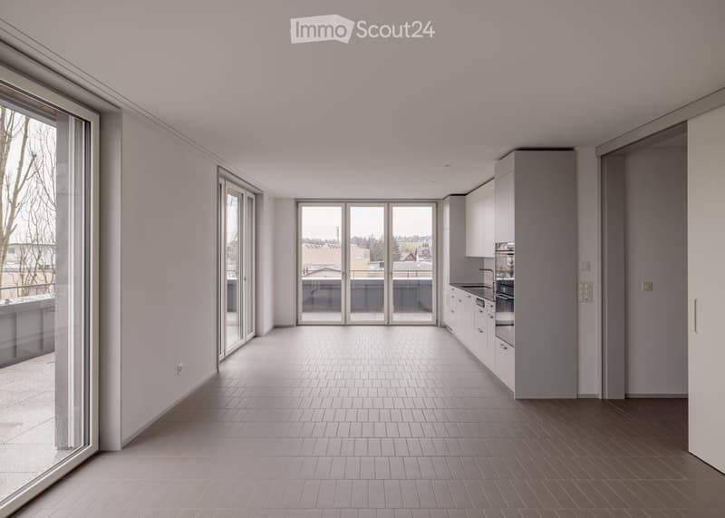 Empty room with sliding glass doors, tiled floor, white walls, kitchen area with cabinets and appliances