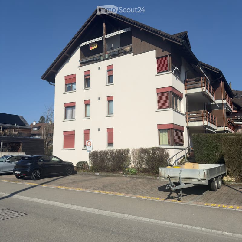 3 story house, white walls, red shutters, brown roof, balcony, cars parked in front