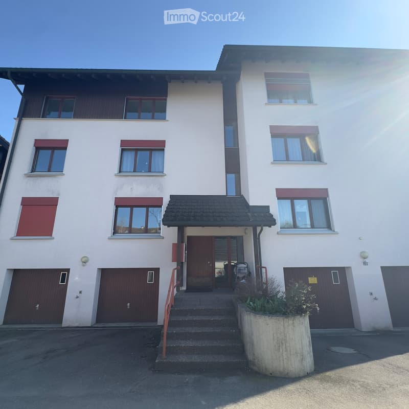 3 story house, white exterior, brown garage doors, 3 windows on each floor, steps leading to the entrance