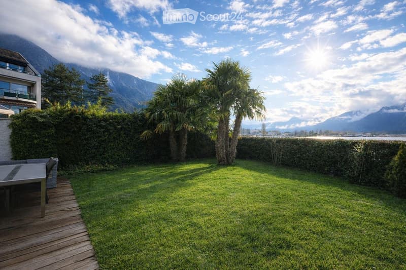 well-maintained lawn, wooden deck, outdoor seating, hedges, palm trees, mountain view