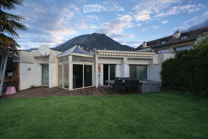 white house, wooden deck, outdoor dining area, green lawn, mountain view
