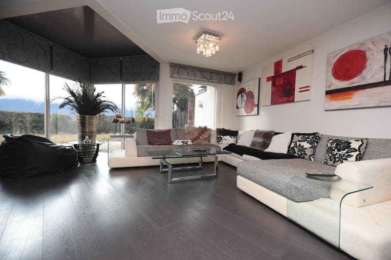 modern living room with large windows, white couch, glass coffee table, decorative pillows, abstract paintings, potted plant, black bean bag