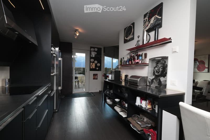 modern kitchen with black cabinets, wooden floor, stainless steel appliances, open door to balcony, shelves with various items