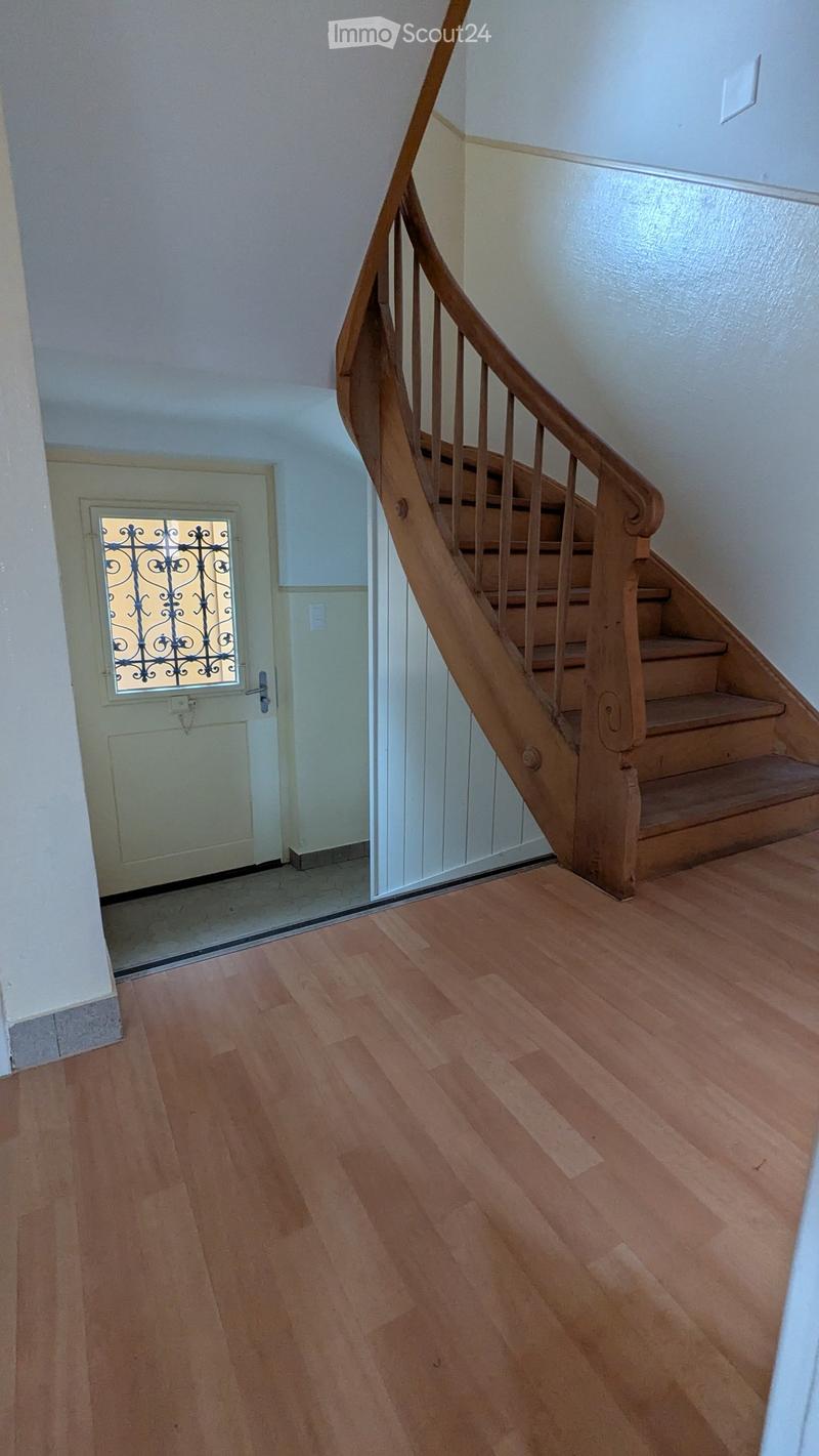 empty room, wooden stairs, closed white door, white walls, wooden floor
