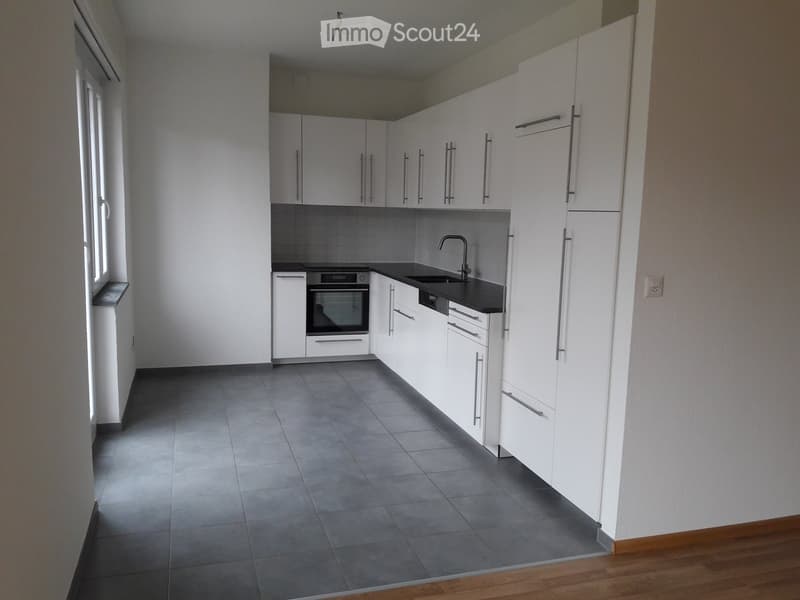modern kitchen with white cabinets, gray tiled floor, black countertop, stainless steel sink, oven, and faucet