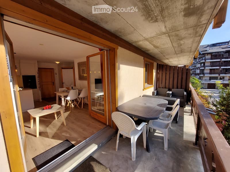 Balcony with table and chairs, wooden floor, glass doors, dining table and chairs inside
