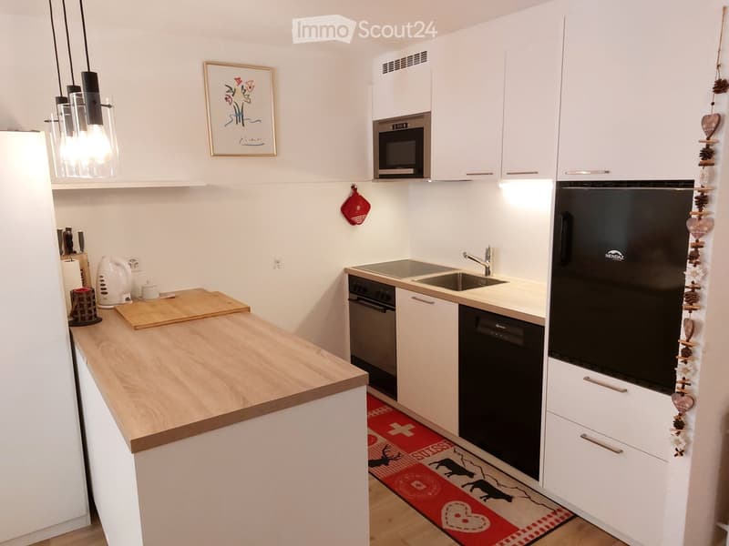 modern kitchen with white cabinets, wooden countertop, black appliances, sink, faucet, microwave, dishwasher, rug, picture frame, hanging pot holder