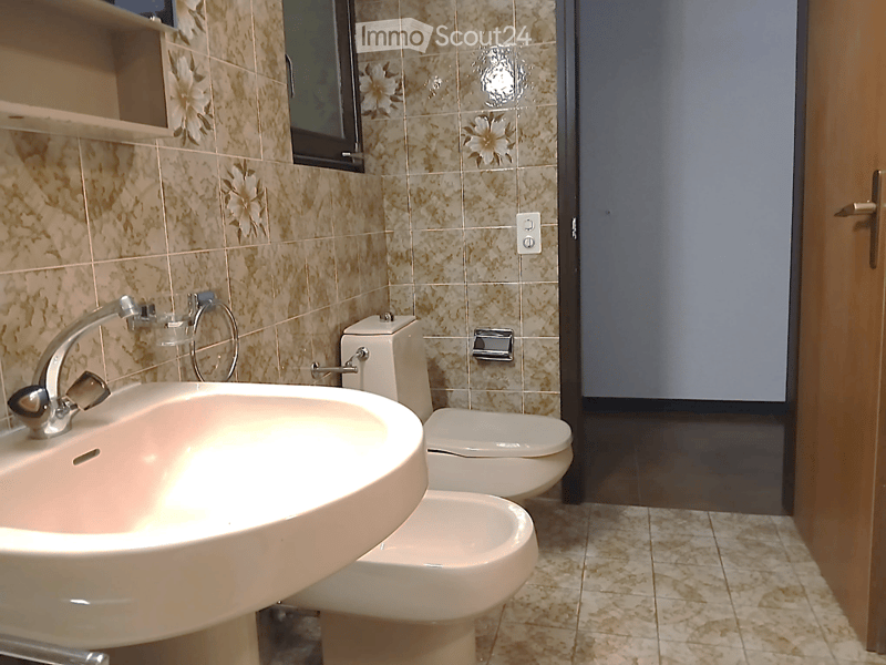 Bathroom with sink, bidet, toilet, and tiled walls and floor.