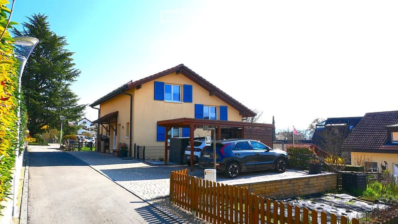 2 story house, yellow exterior, blue shutters, car parked in carport, wooden fence, garden