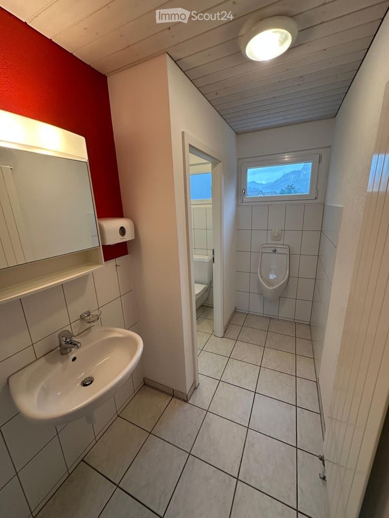 Small bathroom with white tiles, sink, mirror, urinal, toilet, and a window