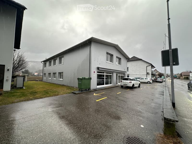 2 story house, gray exterior, multiple windows, parking lot, trash bins, street sign
