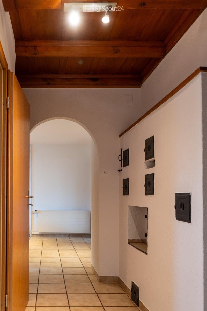 tiled floor, wooden ceiling, arched doorway, white walls, radiator, fireplace