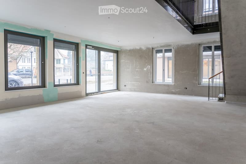 Empty room with concrete floor, glass doors, and windows, under construction