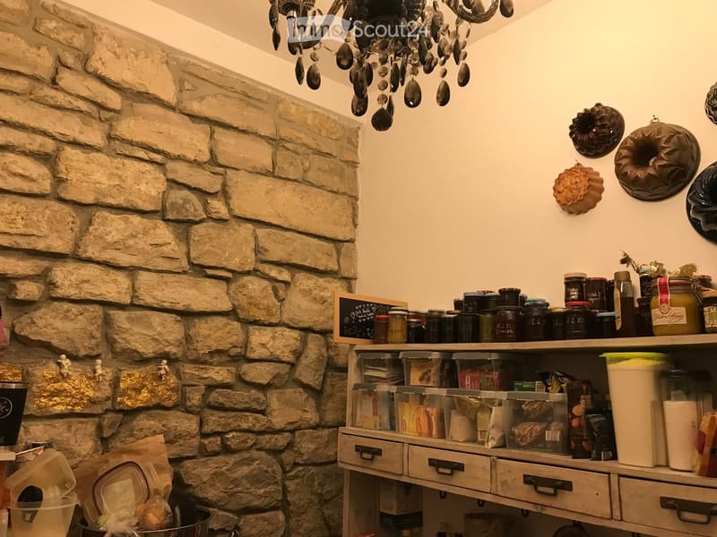 stone wall, chandelier, shelf with jars, storage boxes, and other items