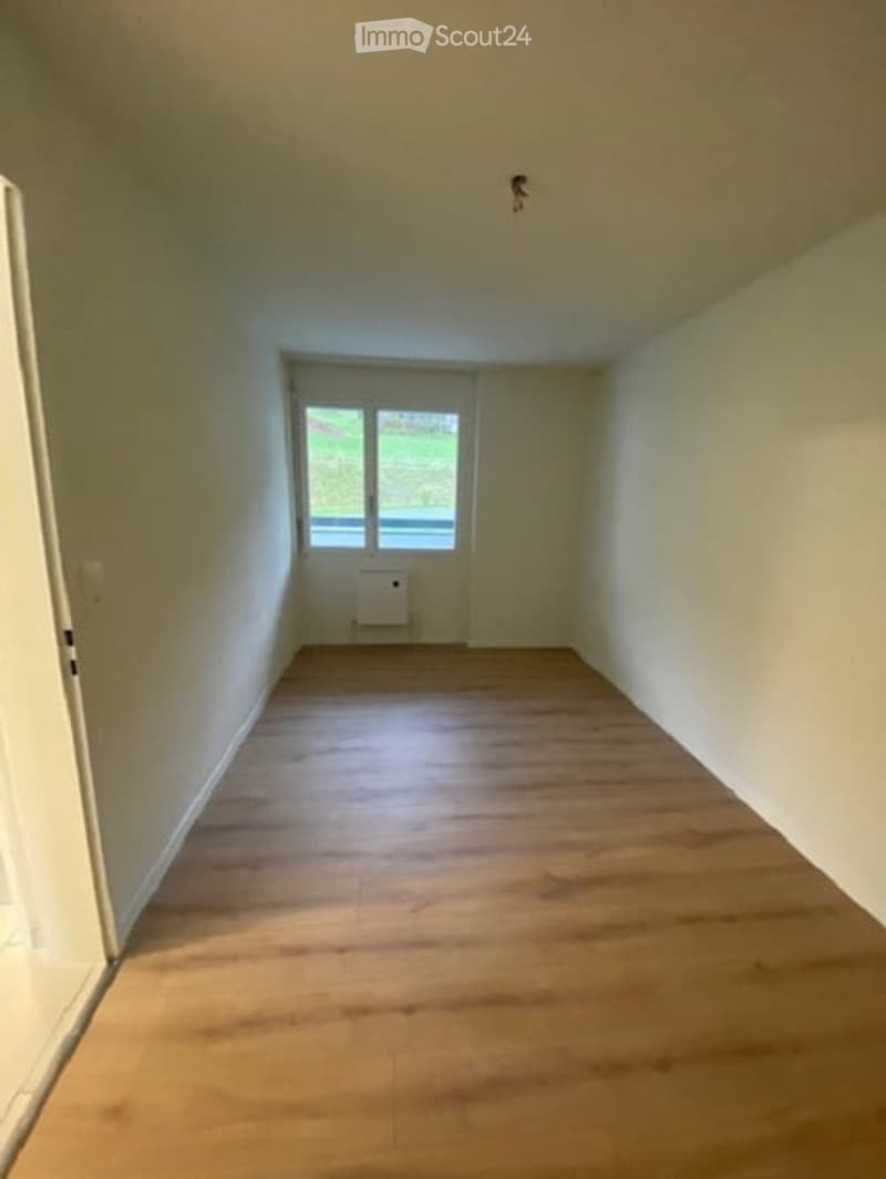 Empty room with wooden floor, white walls, and a window.